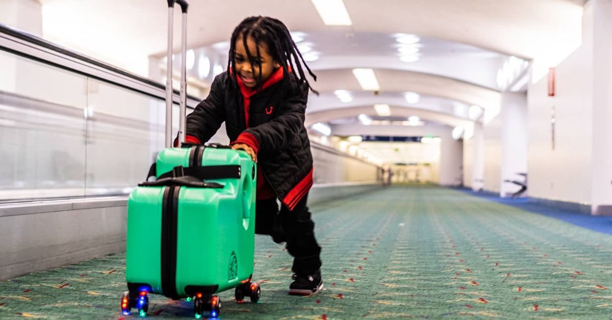 A child carrying a suitcase through an airport